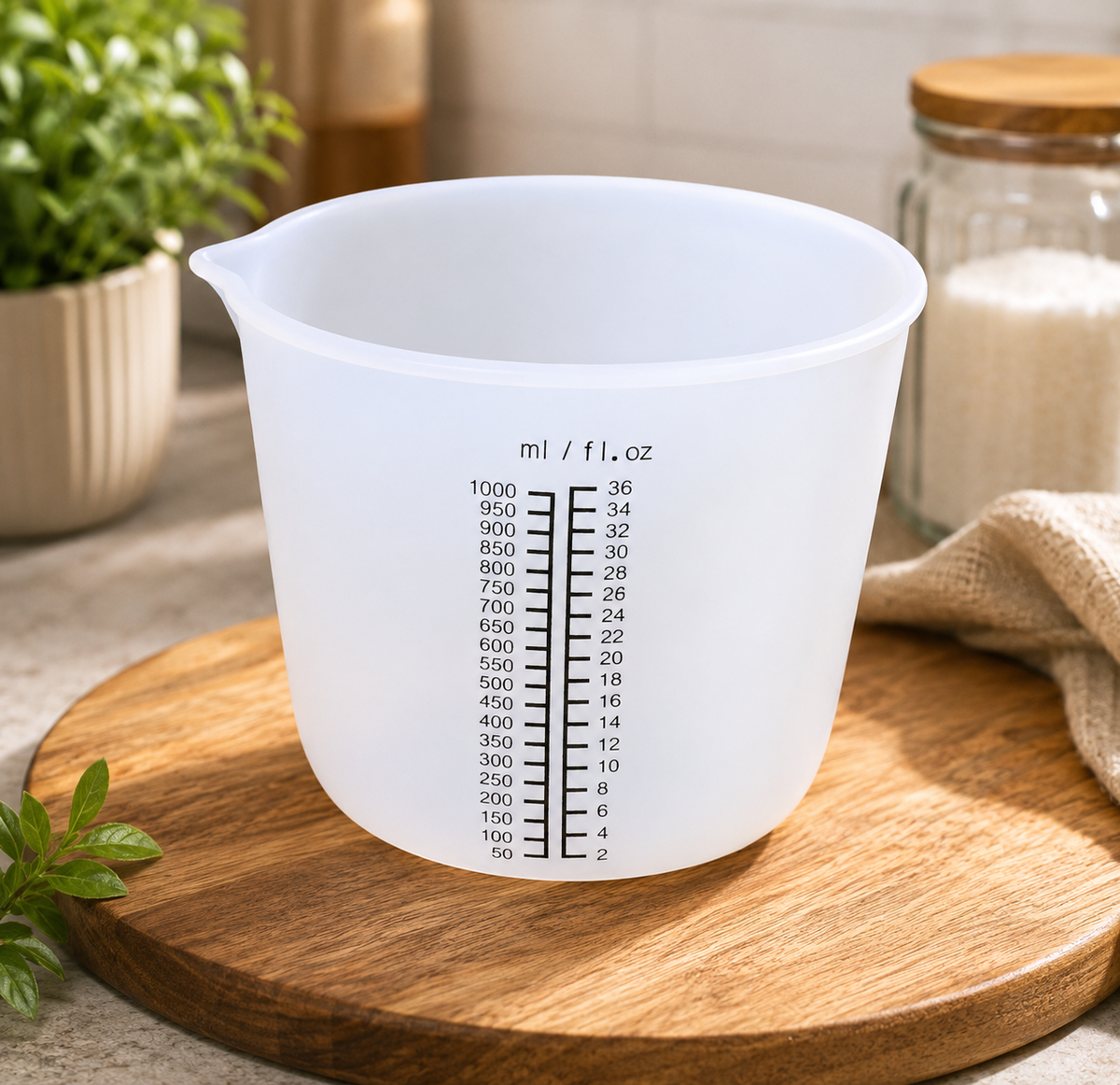 A translucent white plastic measuring cup with black measurement markings, sitting on a round wooden cutting board with kitchen props in the background.