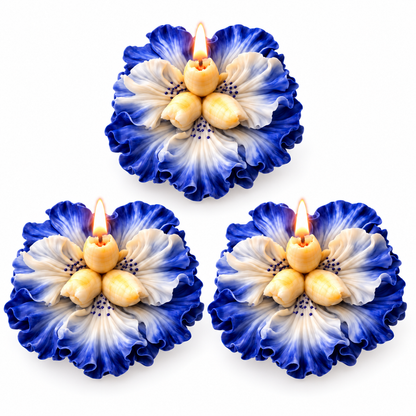 Three blue and white flower-shaped candles arranged in a triangle on a white background, each with a small flame at the center.