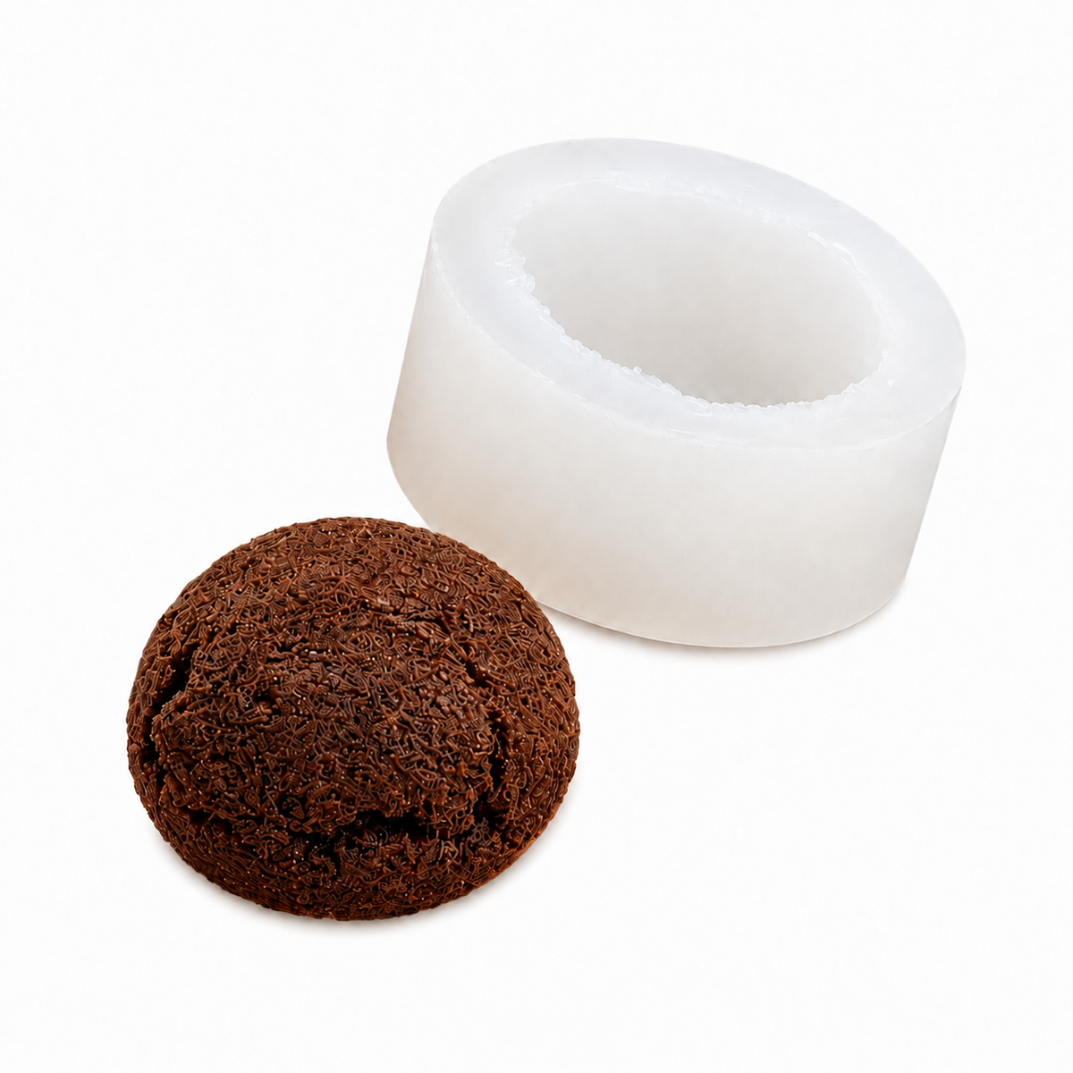 A white cylindrical silicone mold with a hollow center, shown next to a small, textured brown spherical object resembling a cork or compressed earth, on a clean white background.