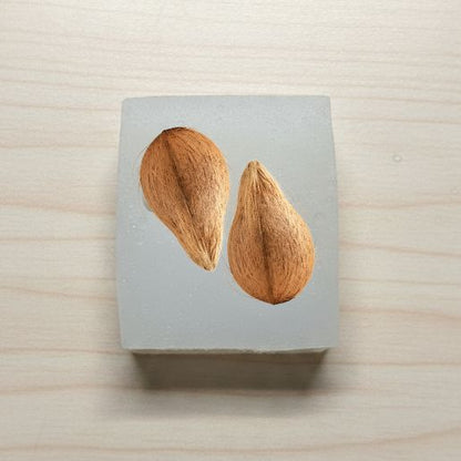 Two almonds on a gray block with a wooden background
