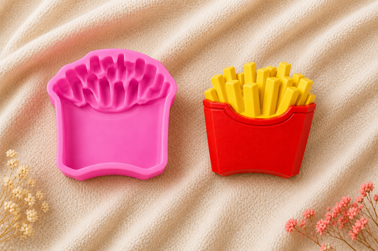 Two novelty French fries shaped items on a beige textured fabric background, one in pink and one in red with yellow fries inside.