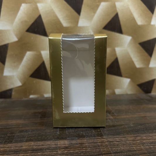 Gold gift box with a white window on a wooden surface with a geometric patterned background