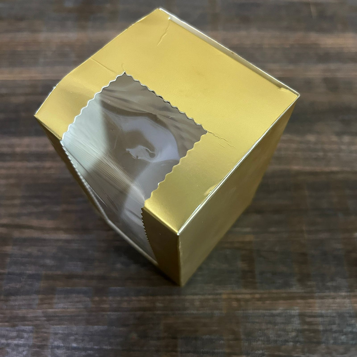 Gold gift box with a cutout on a wooden surface