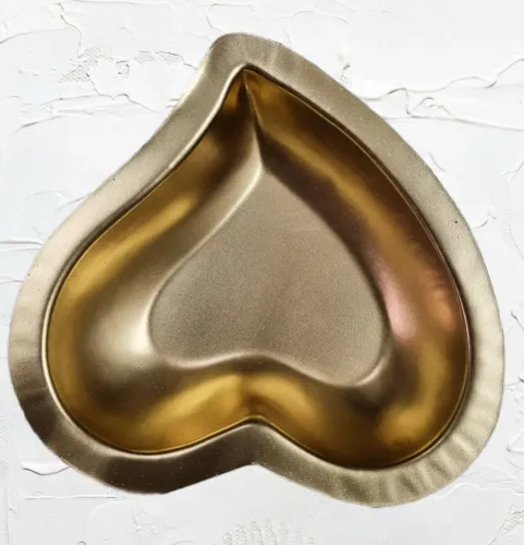 A heart-shaped metal decorative bowl with a silver finish on the exterior and gold-colored interior.