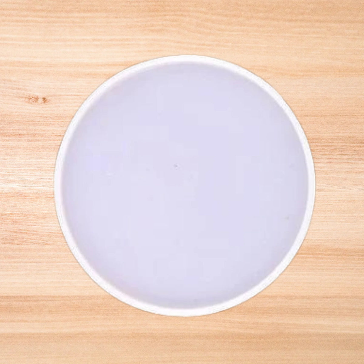 A plain round resin mold placed on a wooden surface.