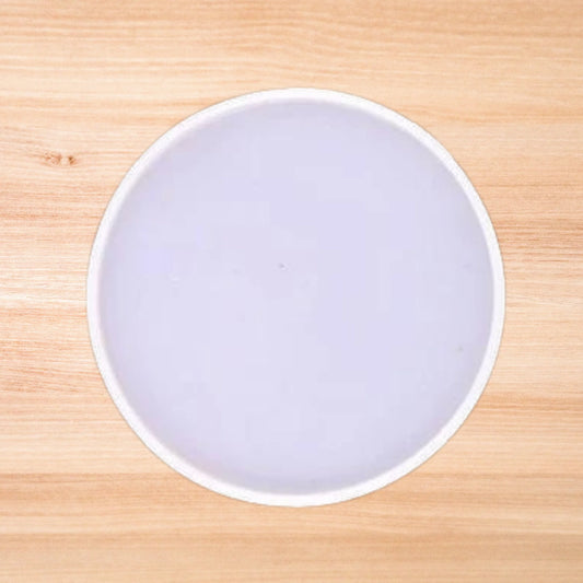 A plain round resin mold placed on a wooden surface.