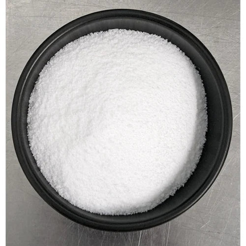 Black bowl filled with white granulated sugar on a metallic surface