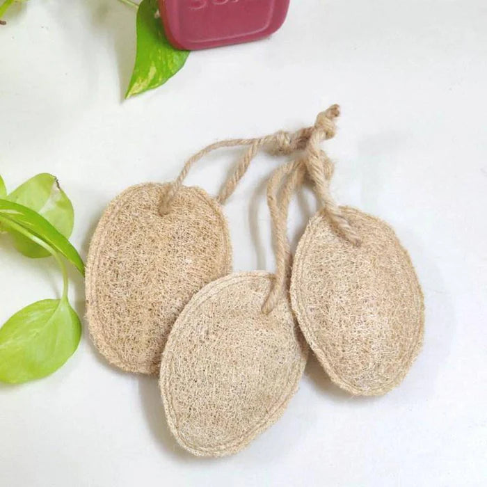 Three oval-shaped loofah sponges tied with twine, displayed on a white surface with a red object in the background.